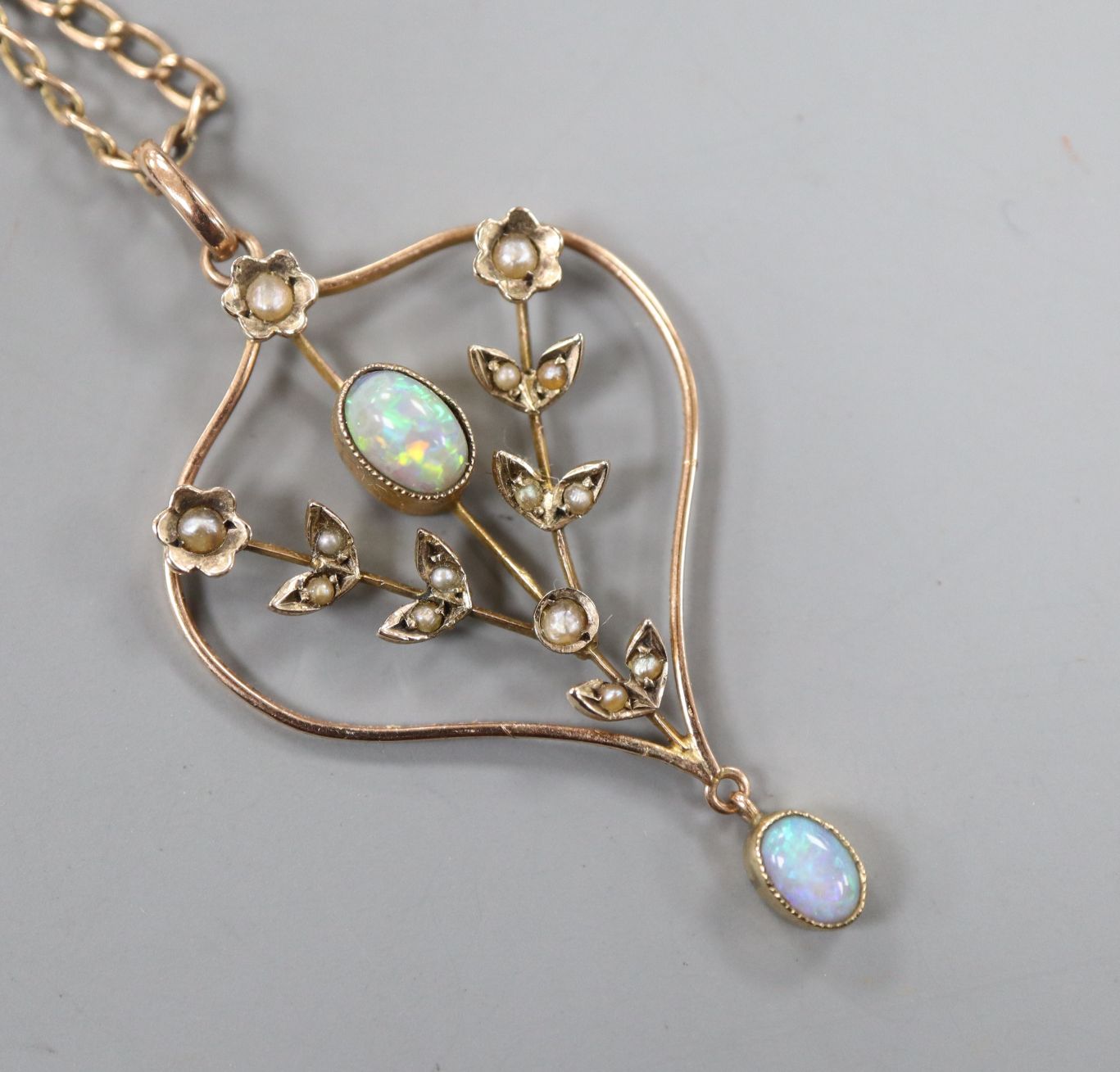 An Edwardian 9ct, white opal and seed pearl set pendant, on a gilt metal chain, pendant 37mm.