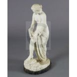A Victorian style carved white marble figure of a woman pulling on her stocking, on variegated black