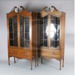 A near pair of Edwardian satinwood banded mahogany bookcases, with swan neck pediments and