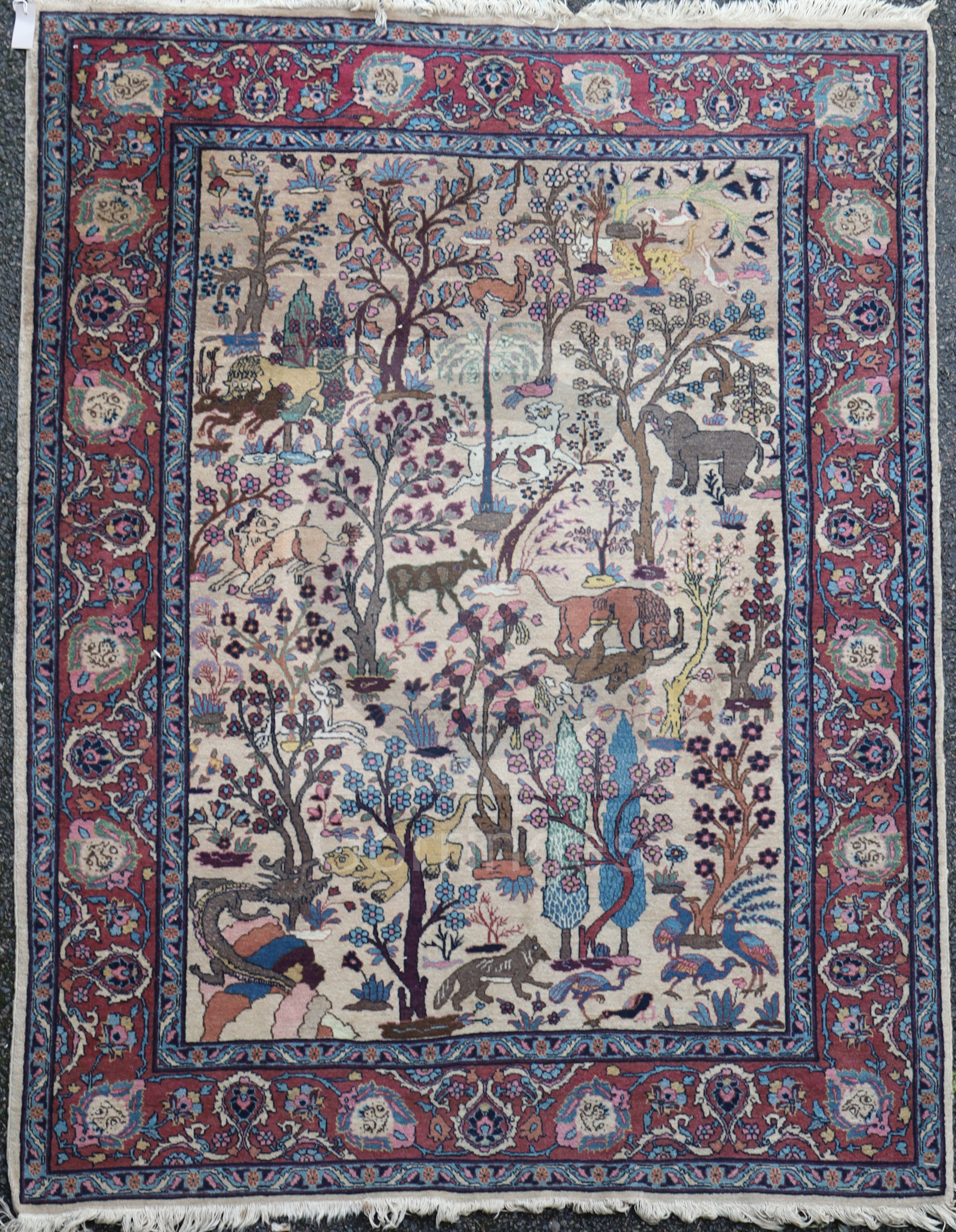 A North West Persian ivory ground rug, with various animals in a field of trees and foliage, with