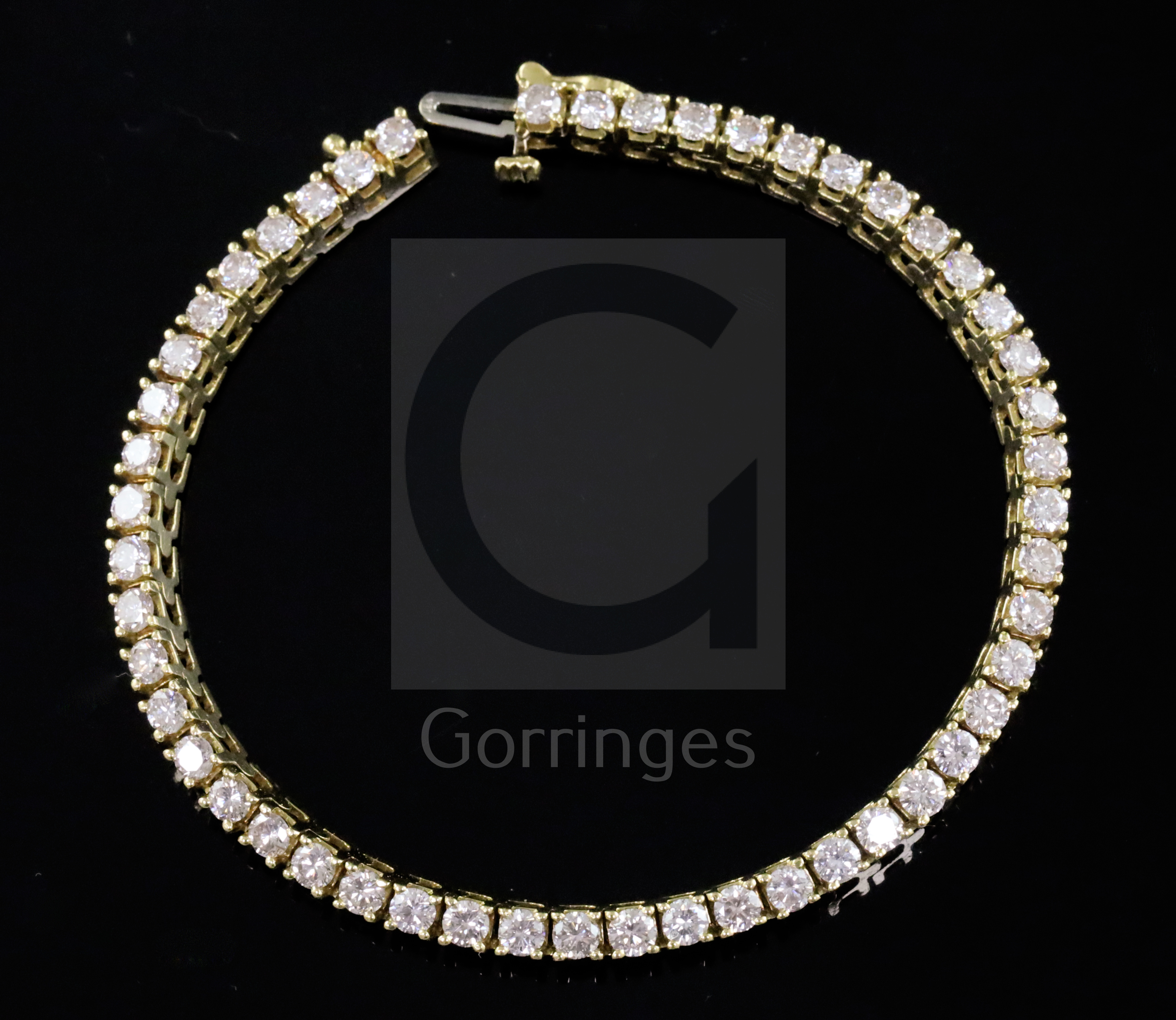 An 18k gold and diamond line bracelet, set with fifty claw set round cut diamonds, 17.5cm.