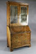 An early 18th century walnut bureau bookcase, with two mirrored doors enclosing shelves, fall