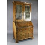 An early 18th century walnut bureau bookcase, with two mirrored doors enclosing shelves, fall