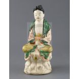 A Chinese Sancai glazed pottery seated figure of Guanyin, Qing dynasty, with scrollwork decoration