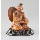 A Chinese boxwood seated figure of a fisherman, with hongmu stand, c.1900, the fisherman with