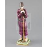 A Russian Gardner porcelain figure of a man holding a staff, mid 19th century, wearing traditional