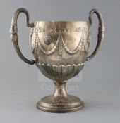 A George III Irish silver two handled pedestal cup, embossed with masks, ribbon bows and swags, on