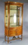 An Edwardian satinwood bowfront display cabinet, with laurel carved frieze, gilt banded central door