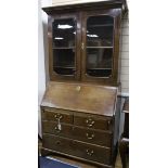 A George III oak and walnut bureau bookcase enclosed by glazed doors over writing fall front and two