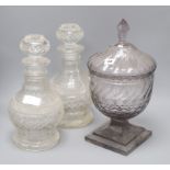 A pair of cut glass decanters and a cut glass lidded pedestal jar height of tallest 40cm