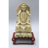 A seated soapstone figure of Guanyin with wood stand Figure excluding base H.33cm