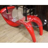 A contemporary red composition oval glass top coffee table W.124cm