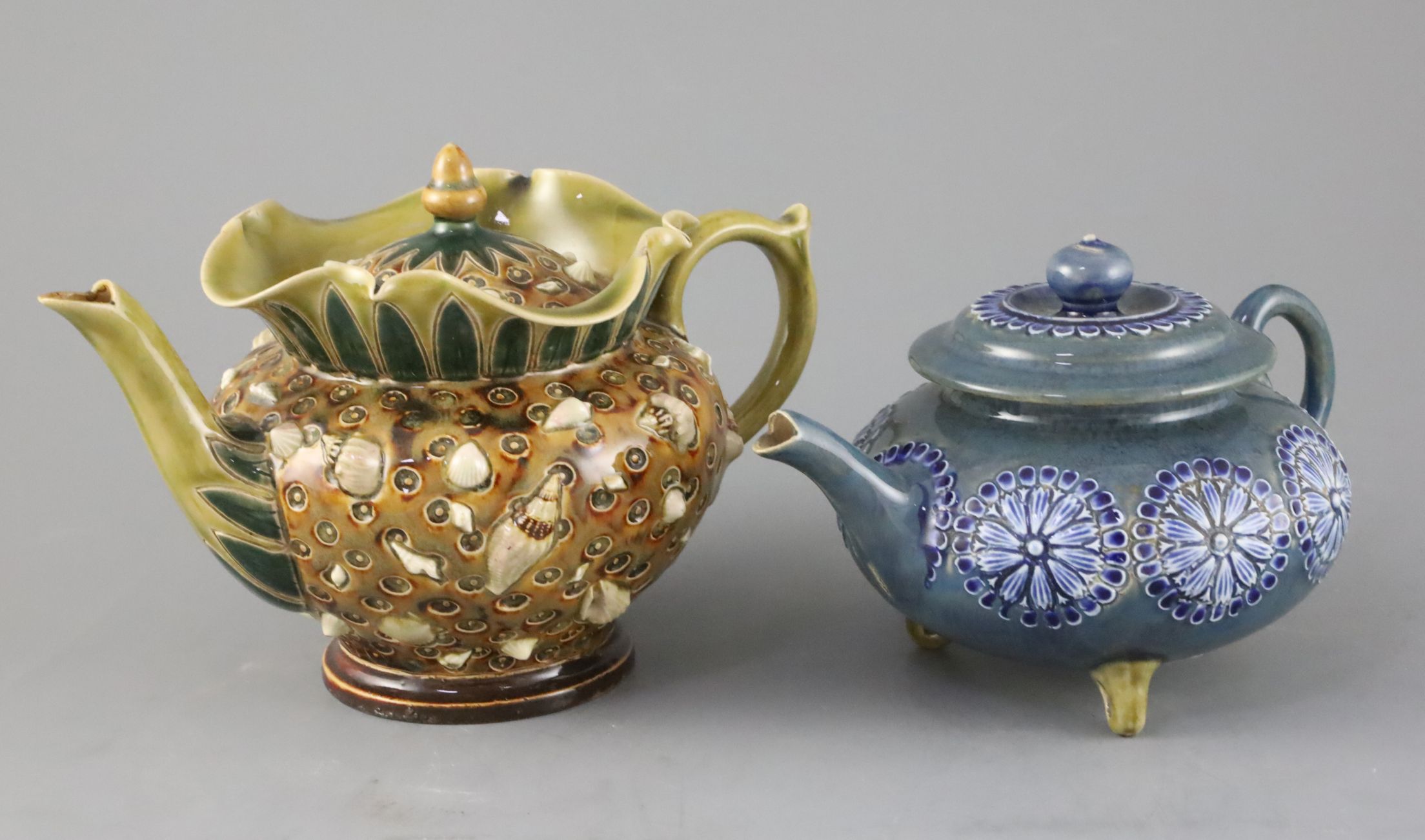 An unusual Doulton Lambeth 'shells' teapot and cover and a flowerhead decorated tripod teapot