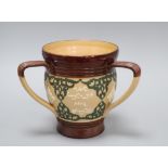 A Doulton Lambeth motto three-handled tyg, c.1895, inscribed 'THE SMALLER THE DRINK....', H. 17.3cm