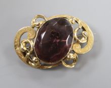 An Edwardian engraved yellow metal mounted amethyst paste set scroll brooch, 43mm.