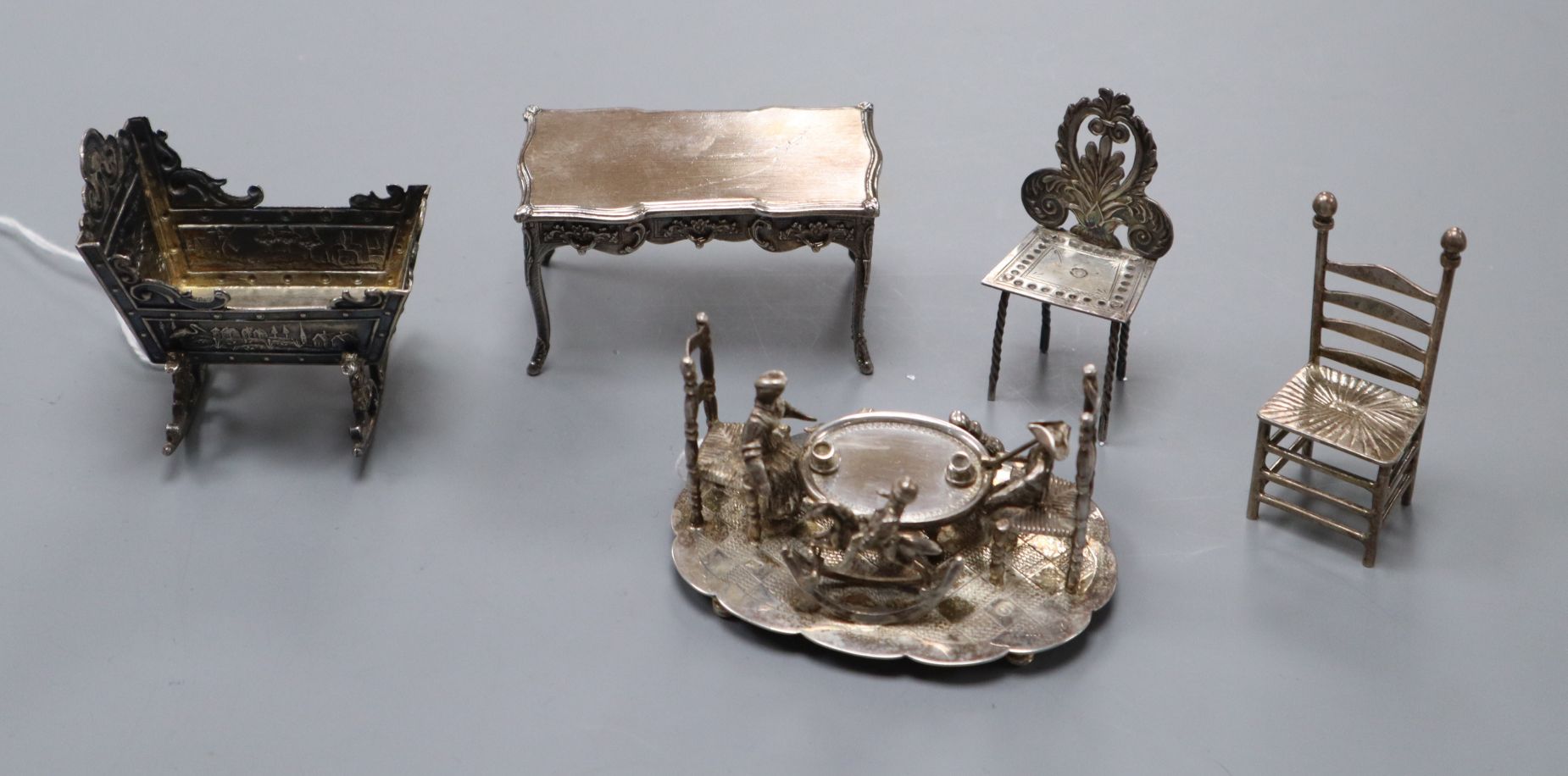 Five assorted continental white metal miniature items including a Dutch embossed cradle and a