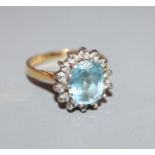 A modern 18ct gold, aquamarine and diamond set oval cluster dress ring, size M.