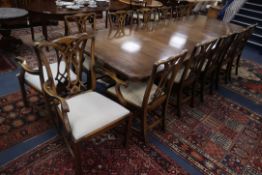 A reproduction mahogany twin pillar extending dining table together with twelve Georgian style