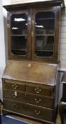 A George III oak and walnut bureau bookcase enclosed by glazed doors over writing fall front and two