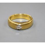 A yellow metal (tests as 18ct) and gypsy set solitaire diamond ring, the stone weighing