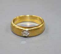 A yellow metal (tests as 18ct) and gypsy set solitaire diamond ring, the stone weighing