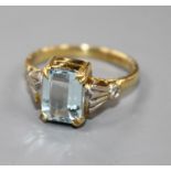 An 18ct and emerald cut aquamarine dress ring, with diamond set shoulders, size N.