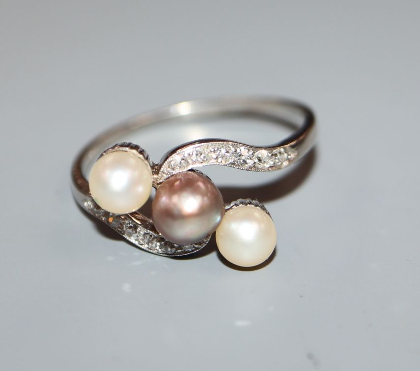 A three-cultured pearl, diamond and platinum set crossover ring, size V.