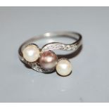 A three-cultured pearl, diamond and platinum set crossover ring, size V.