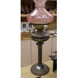 A brass oil lamp with cranberry shade height 72cm