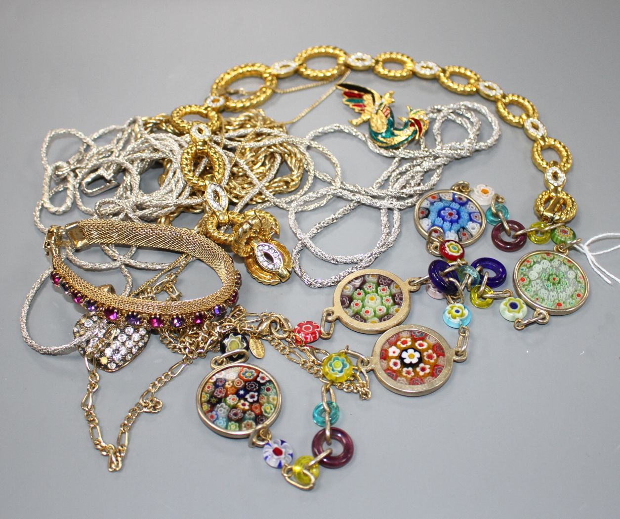 Seven assorted costume necklaces including a millefiore glass necklace, a costume bird brooch and