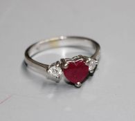 A modern 750 white metal, claw set heart shaped ruby and two round cut diamond set dress ring,