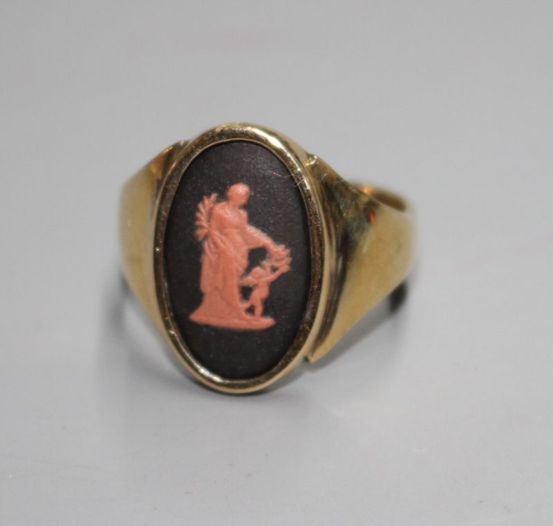 A yellow metal and oval Wedgwood plaque set ring, decorated with a lady and cherub, size N.