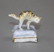 A rare Staffordshire toy porcelain figure of a cat with arched back, on a cushion, c.1835-50,