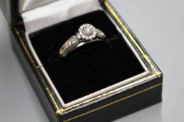 A modern 18k white metal and diamond cluster flower head ring, with diamond set shoulders, total