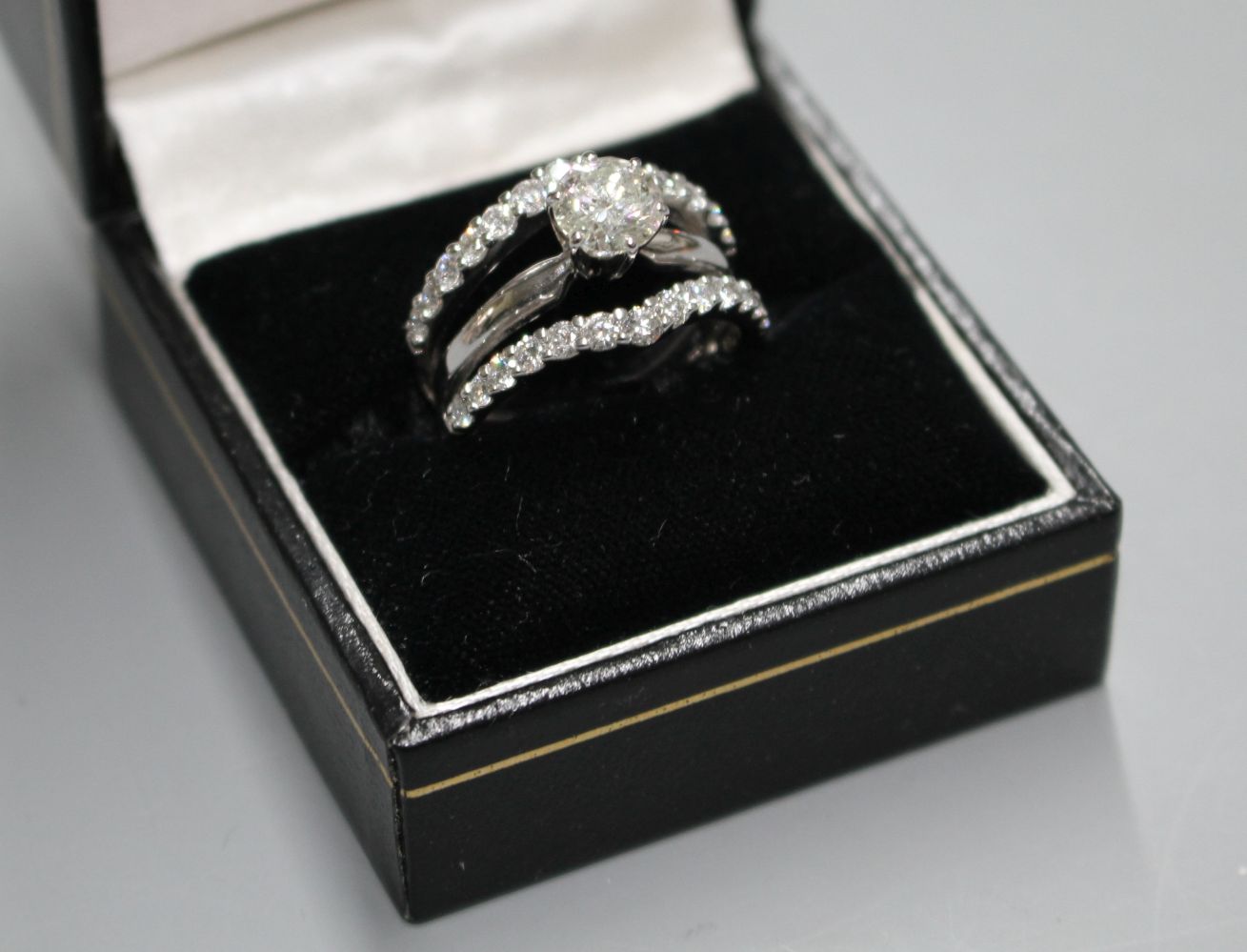 A modern 14kt white metal and triple band diamond dress ring, with two herringbone bands, each set