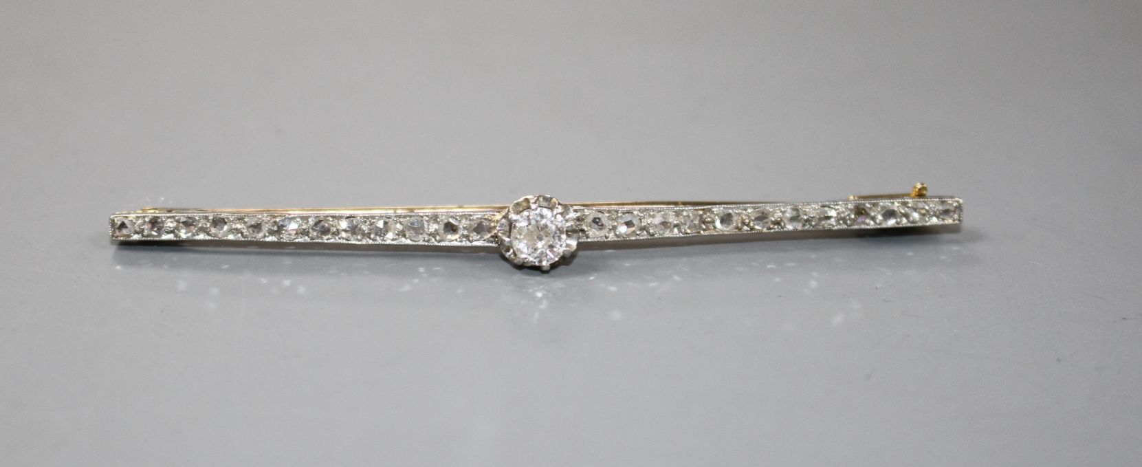 A 1920's yellow and white metal, diamond bar brooch, with central old cut diamond and millegrain set