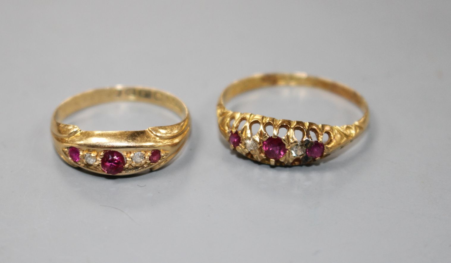 Two early 20th century 18ct gold, ruby and diamond set dress rings, sizes- N(3 stone) and R. Gross