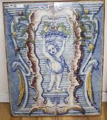 A Continental maiolica tile panel, depicting a putto holding aloft a basket of fruit, overall 90 x