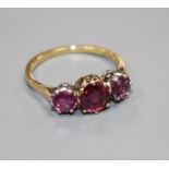 An 18ct and three stone ruby set dress ring, size M, gross 2.7 grams. Condition: Two outer stones