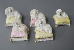 Five Staffordshire porcelain toy figures of four poodles and a King Charles spaniel recumbent on a