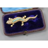 An Edwardian yellow metal(stamped 15), turquoise and seed pearl set lizard brooch, with gem set