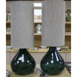 A pair of green glass lamp bases with cylindrical fabric shades, height overall 94cm, diameter