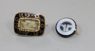 A Victorian yellow metal and black enamel mourning brooch with plaited hair beneath a glazed panel