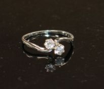 An 18ct and Plat, two stone diamond crossover ring, size P/Q, gross weight 2.5 grams. Condition: