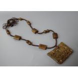 A Chinese hardstone necklace, with carved and inscribed plaque and brown fabric strung beads, plaque