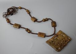 A Chinese hardstone necklace, with carved and inscribed plaque and brown fabric strung beads, plaque