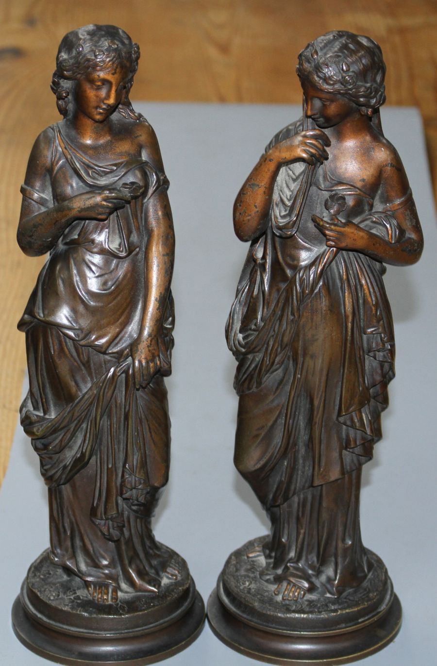 A pair of late 19th century French bronze figures of muses, each standing holding flowers, height