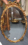 An oval gilt composition wall mirror with ribbon tied decoration, W.64cm H.100cm Condition: Good