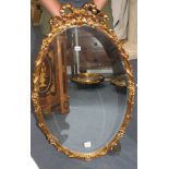 An oval gilt composition wall mirror with ribbon tied decoration, W.64cm H.100cm Condition: Good