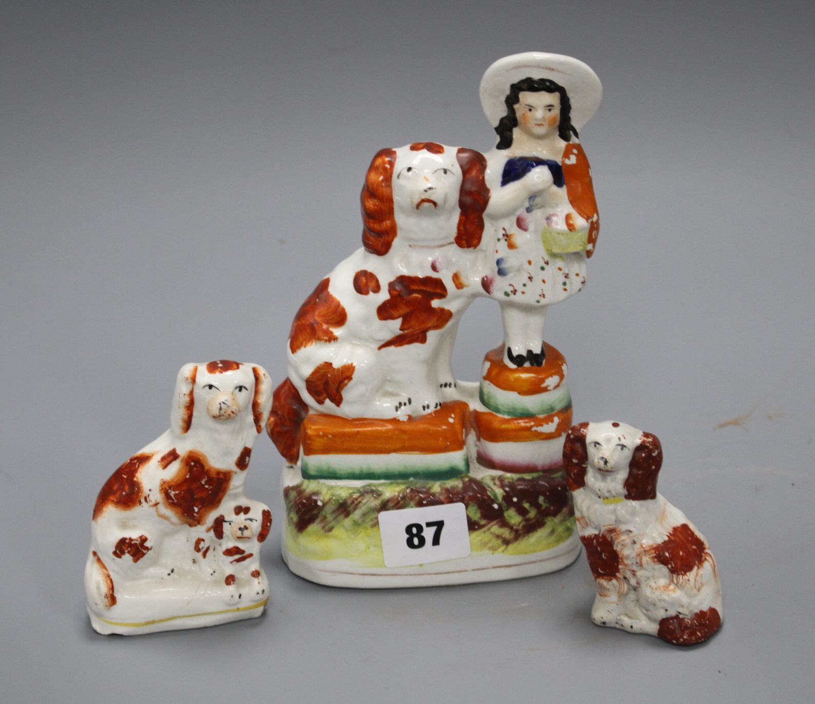 A Victorian Staffordshire girl and spaniel group, height 19cm and two smaller Staffordshire dogs,
